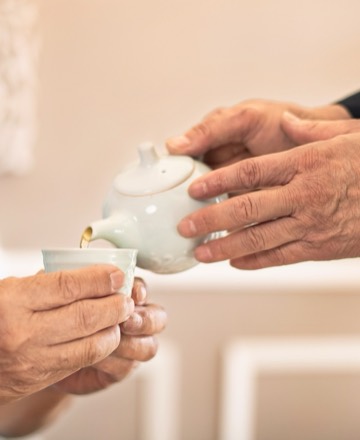 Hands pouring tea at a Clever Care community gathering